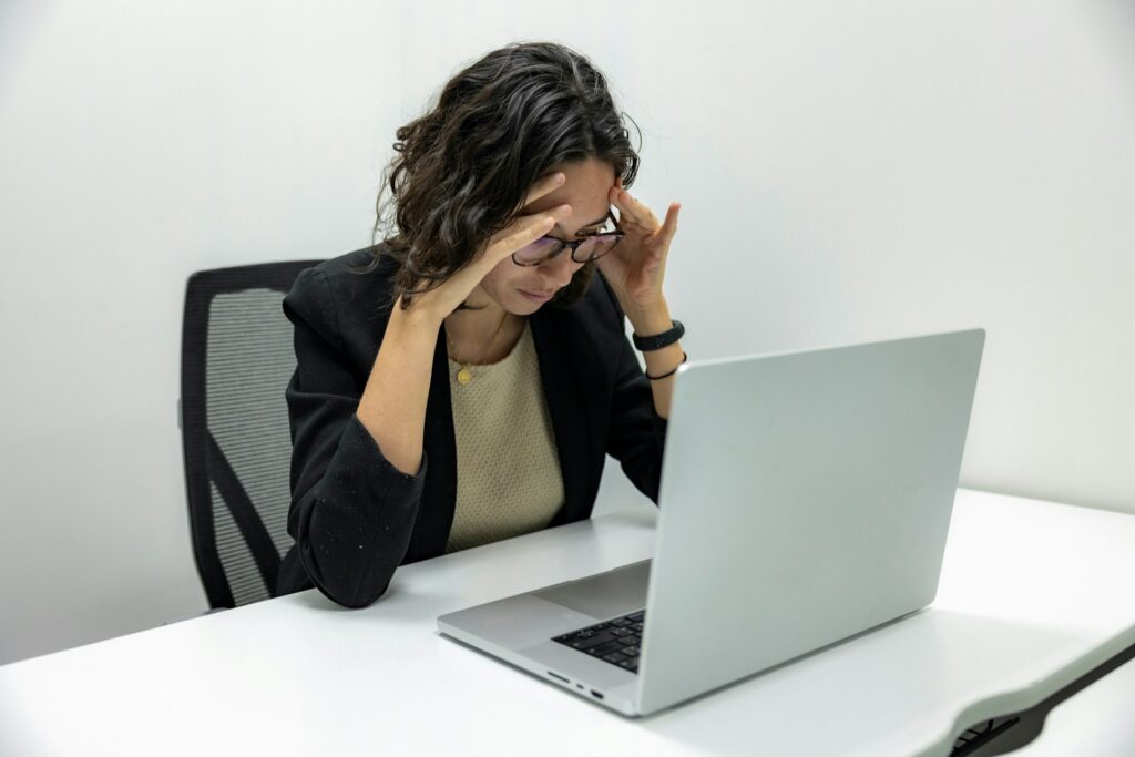Employee feeling stressed while working on a laptop at her desk.