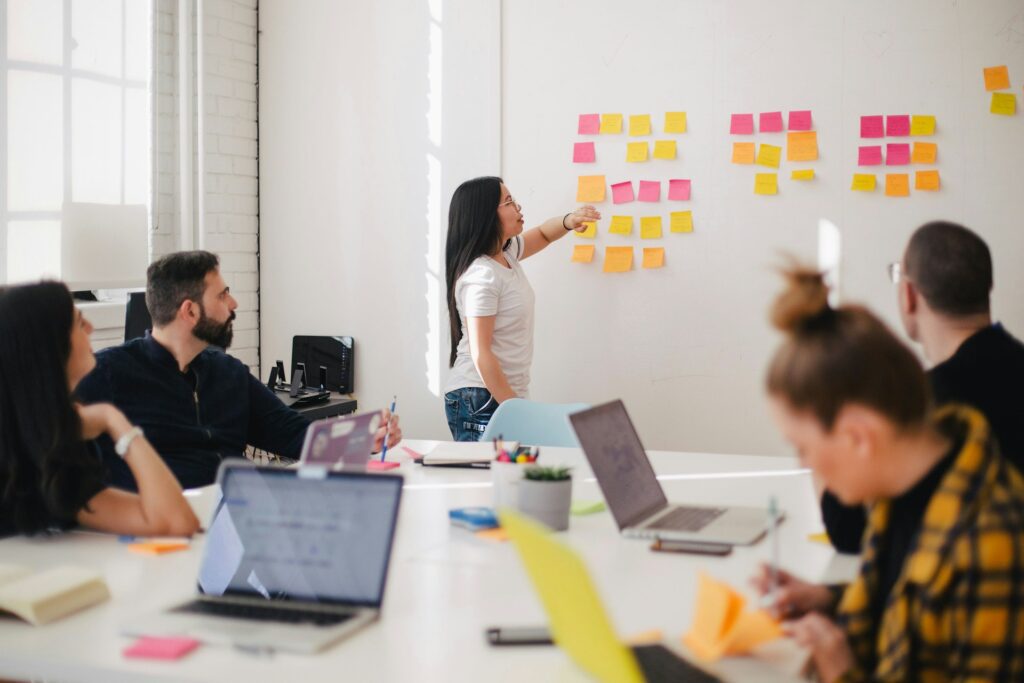 woman in an office pointing to sticky notes on a wall