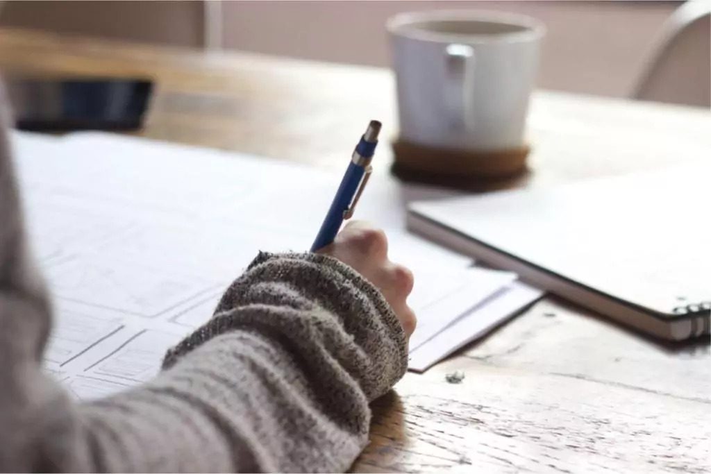 Close-up image of a person writing with a pen