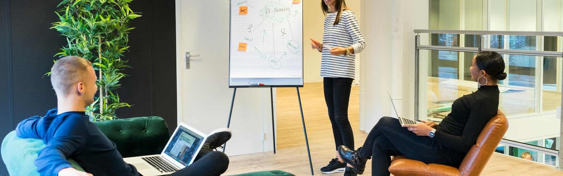 Woman giving a presentation on a whiteboard with two people watching