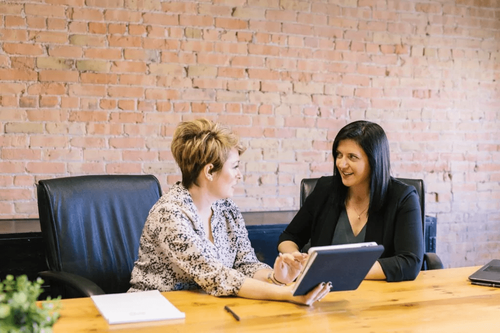 Two women talking at boardroom table