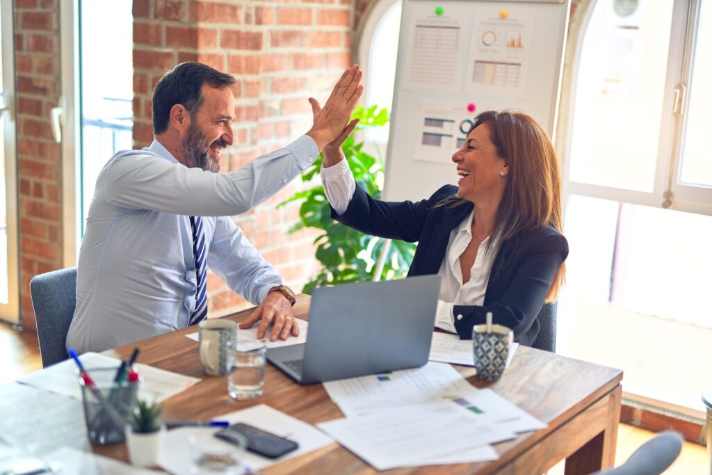 A man and woman are high-fiving in an office