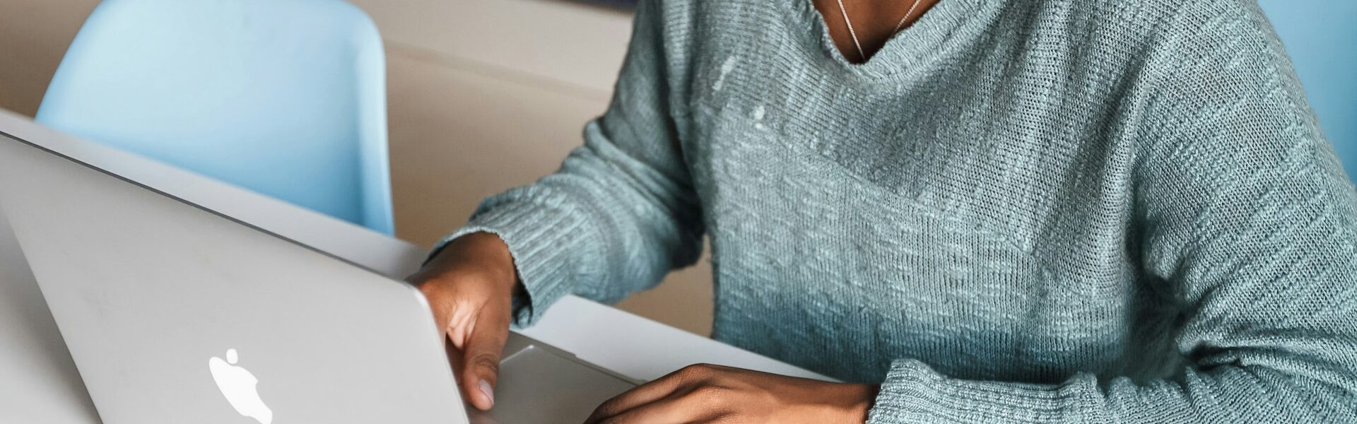 Woman smiling at her computer typing to highlight her skills.