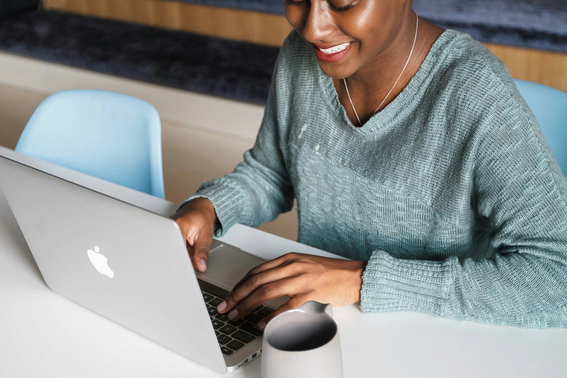 Woman smiling at her computer typing to highlight her skills.