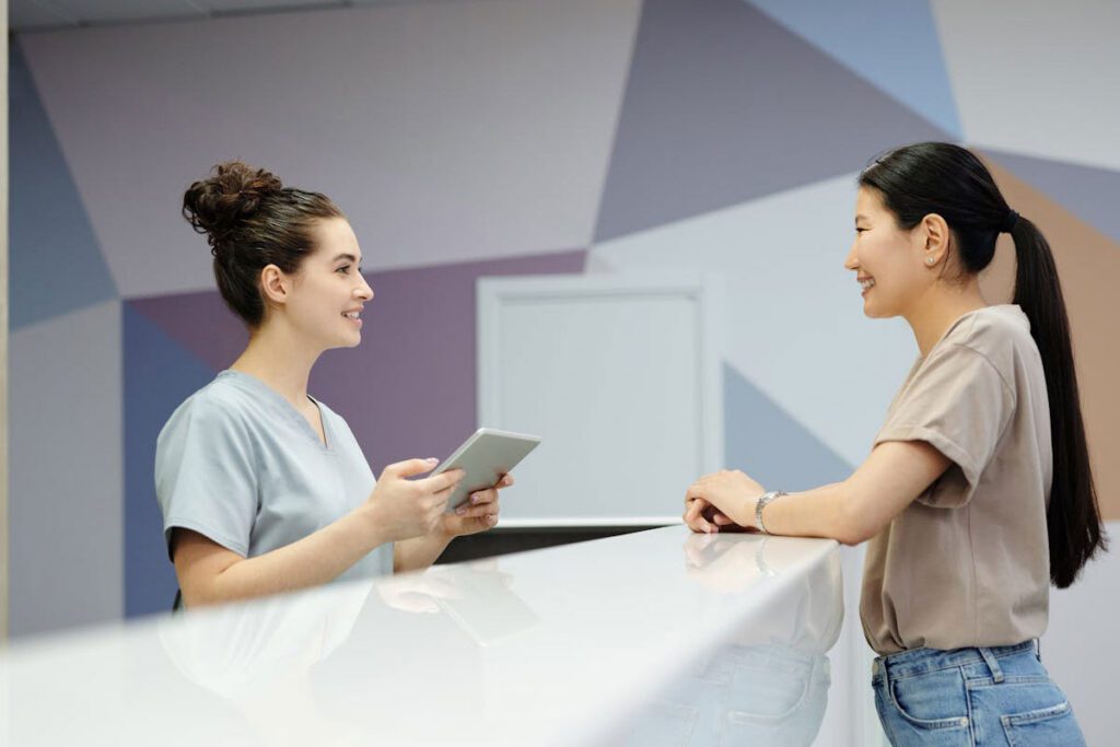 A woman talking to a receptionist at the front desk