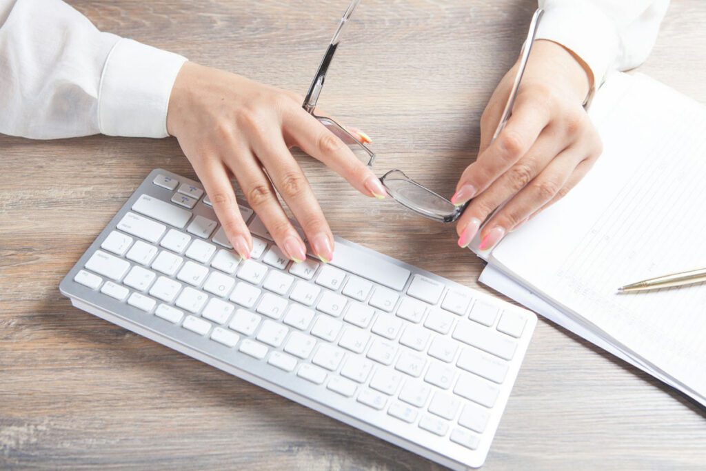 Hands holding glasses near a computer keyboard