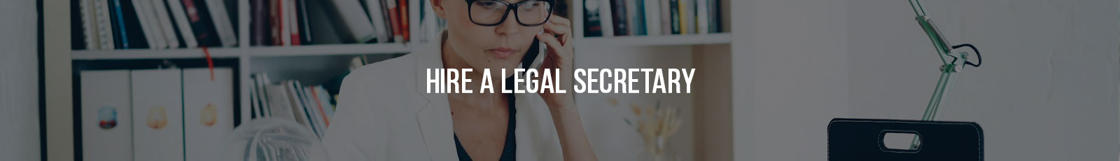 Professional legal secretary working at a desk while on the phone, reviewing information