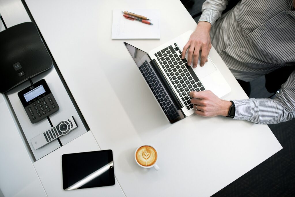 Employer reviewing hiring plan on laptop with coffee